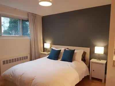 a bedroom with a large white bed with blue pillows at Bright and Spacious Studio Apartment in Montréal