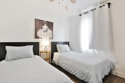 two beds in a room with white walls at Comfortable 2-BEDROOM APARTMENT - Free and plentiful PARKING - 10 minutes to AIRPORT and 15 minutes to DOWNTOWN Montreal - Near Popular Waterfront Restaurants - located in Beautiful Lachine in Montréal