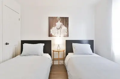 two beds in a room with white walls at Comfortable 2-BEDROOM APARTMENT - Free and plentiful PARKING - 10 minutes to AIRPORT and 15 minutes to DOWNTOWN Montreal - Near Popular Waterfront Restaurants - located in Beautiful Lachine in Montréal