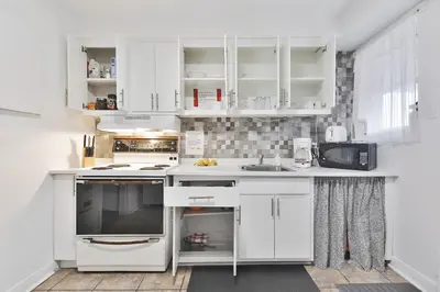 a white kitchen with white cabinets and a sink at Comfortable 2-BEDROOM APARTMENT - Free and plentiful PARKING - 10 minutes to AIRPORT and 15 minutes to DOWNTOWN Montreal - Near Popular Waterfront Restaurants - located in Beautiful Lachine in Montréal