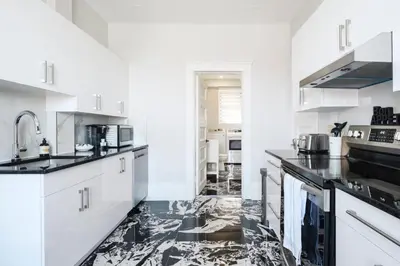 a kitchen with white cabinets and black counter tops at The Parkview By MTLVacationRentals in Montréal