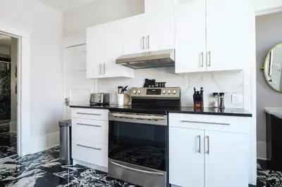 a kitchen with white cabinets and a black stove at The Parkview By MTLVacationRentals in Montréal