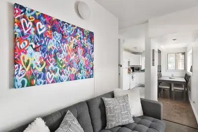 a living room with a couch and a painting on the wall at 250 METERS to METRO BERRI UQAM - Spacious fully equipped APARTMENTS - 1 FREE PARKING per unit - in-unit Washer & Dryer - fully stocked KITCHEN - WORKSPACE PROVIDED - FAST WIFI - 5 minute walk to the FAMOUS ST CATHERINE & ST DENIS STREET in Montréal