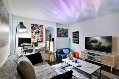 a living room with a couch and a flat screen tv at 250 METERS to METRO BERRI UQAM - Spacious fully equipped APARTMENTS - 1 FREE PARKING per unit - in-unit Washer & Dryer - fully stocked KITCHEN - WORKSPACE PROVIDED - FAST WIFI - 5 minute walk to the FAMOUS ST CATHERINE & ST DENIS STREET in Montréal
