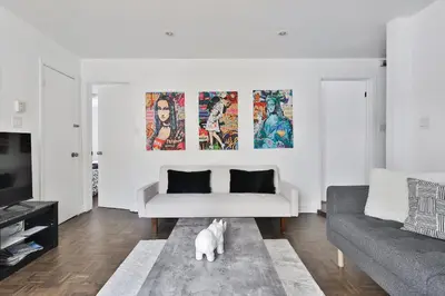 a living room with a couch and a dog on a rug at 250 METERS to METRO BERRI UQAM - Spacious fully equipped APARTMENTS - 1 FREE PARKING per unit - in-unit Washer & Dryer - fully stocked KITCHEN - WORKSPACE PROVIDED - FAST WIFI - 5 minute walk to the FAMOUS ST CATHERINE & ST DENIS STREET in Montréal