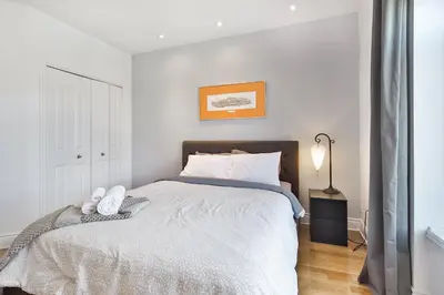 a white bedroom with a bed and a lamp at STUNNING full APARTMENTS - stocked KITCHENS - WASHER & DRYERS - WORKSPACE PROVIDED - FAST WIFI - LOCATED on the FAMOUS ST Denis street - Near METRO MONT ROYAL in Montréal