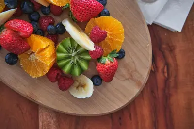 a plate of fruit on top of a wooden table at Étoile du Lac Lyster - Spa & Vue sur le Lac in Coaticook