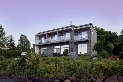 a house with a dog standing in front of it at Étoile du Lac Lyster - Spa & Vue sur le Lac in Coaticook