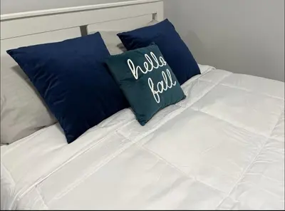 a white bed with two blue pillows on it at Fantastique 3 chambres modernes au cœur de la ville in Montréal