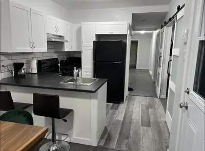 a kitchen with white cabinets and a black refrigerator at Fantastique 3 chambres modernes au cœur de la ville in Montréal