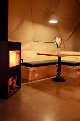 a tent room with a table and a fireplace at Mi-clos - luxury pods with private jacuzzi and sauna in Orford