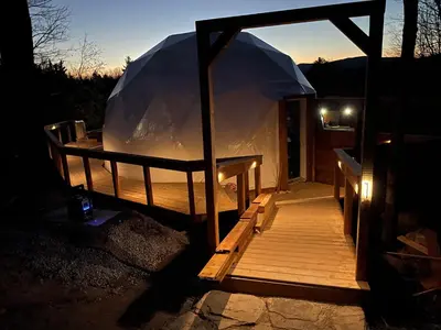 a wooden deck with a tent in the dark at Mi-clos - luxury pods with private jacuzzi and sauna in Orford
