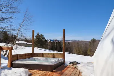 a hot tub on a deck in the snow at Mi-clos - luxury pods with private jacuzzi and sauna in Orford