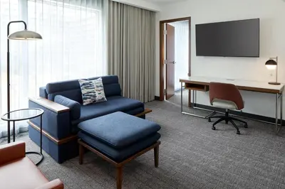 a living room with a chair and a desk with a tv at Courtyard by Marriott Montreal Laval in Laval