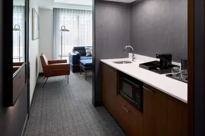 a kitchen with a sink and a living room at Courtyard by Marriott Montreal Laval in Laval