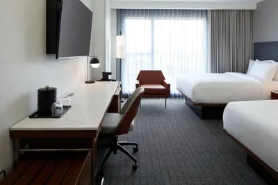 a hotel room with two beds and a desk at Courtyard by Marriott Montreal Laval in Laval