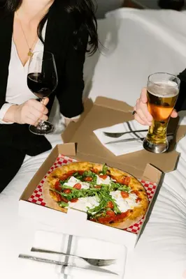 a woman sitting at a table with a pizza and two glasses of beer at Courtyard by Marriott Montreal Laval in Laval