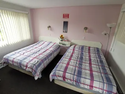 two beds in a bedroom with pink walls at Motel Sainte Catherine in Sainte-Catherine